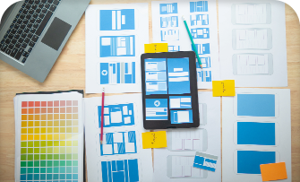 Tablet and sketches of app designs with color palettes on a table.