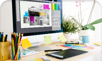 Desk with graphic design software on screen, surrounded by colorful stationery.